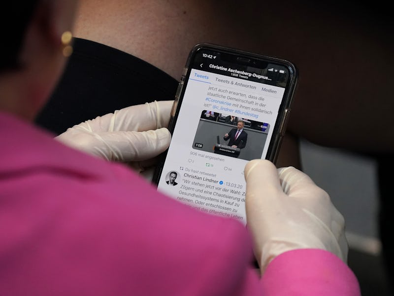 BERLIN, GERMANY - MARCH 25: A member of the Bundestag wears protective gloves as she follows a Twitt...