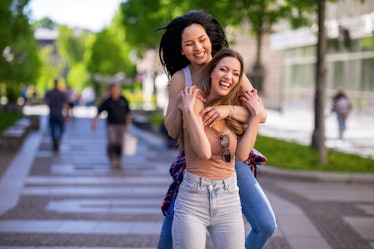 two friends piggybacking as they walk down the street, chatting about cancer libra friendship compat...