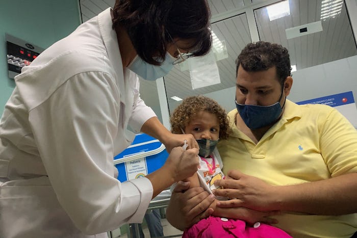 TOPSHOT - Pedro Montano holds his daughter Roxana Montano, 3, while she is being vaccinated against ...