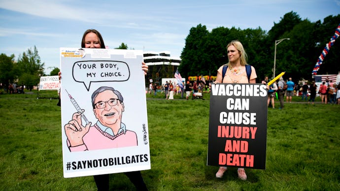 Two women hold anti-vaccination signs during a protest against Governor Jay Inslee's stay-at-home or...