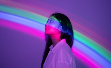 young woman lit by rainbow-colored lights as she looks to the left, reflecting on how october 15, 20...
