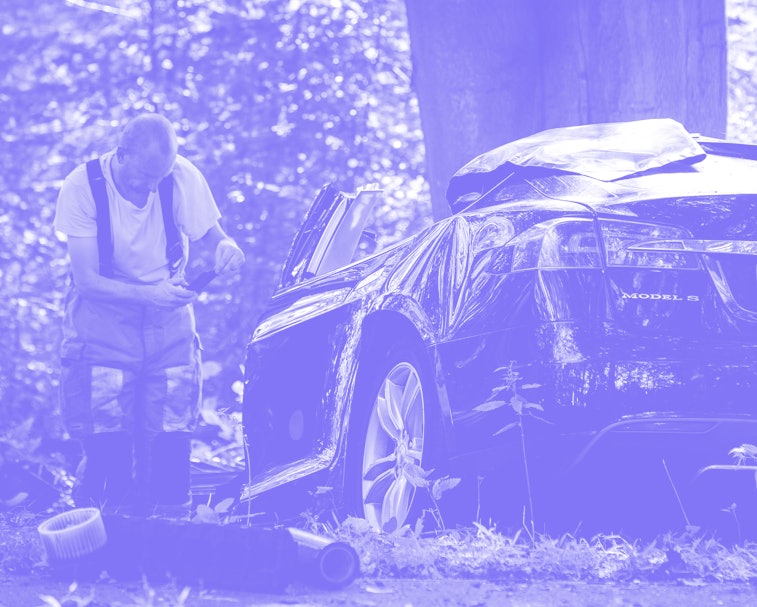 A rescue worker takes a picture around the spot where a Tesla slammed into a tree in Baarn, on Septe...
