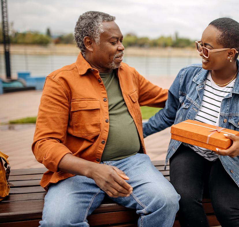 Young woman giving gift to her father and saying "Happy birthday dad," for which she'll need Instagr...
