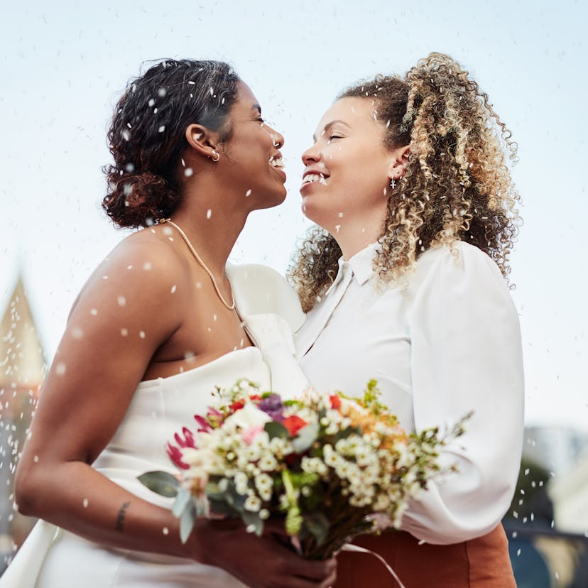 two women smile at each other during their wedding, one of the best days to get married in 2022 acco...
