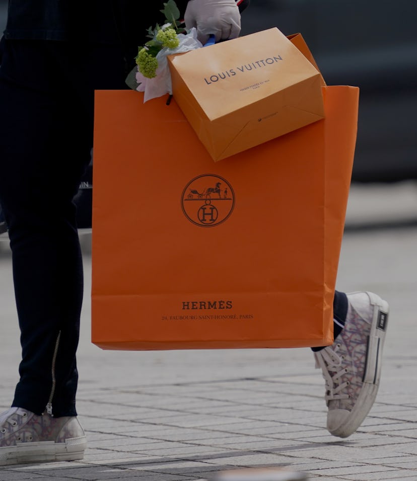 PARIS, FRANCE - MAY 11: A passerby wears Dior B23 sneakers and holds a Hermes orange shopping paper ...