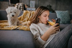 A woman plays wordle on her phone while drinking orange juice. Need games to play after Wordle? Thes...