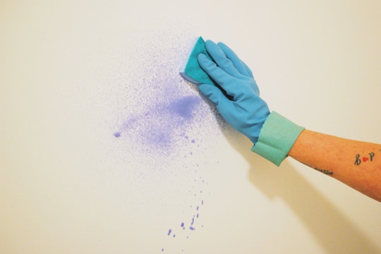 a hand scrubbing a pen mark on the wall