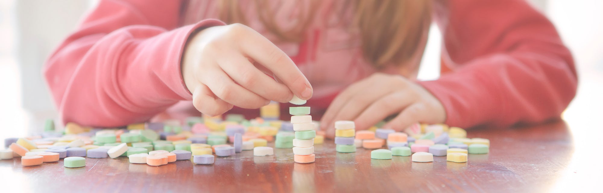 little girl stacking conversation hearts for a valentine's day game for kids idea