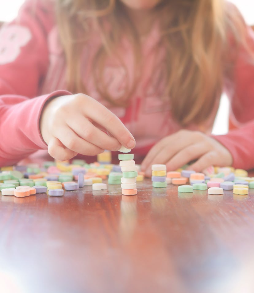 little girl stacking conversation hearts for a valentine's day game for kids idea