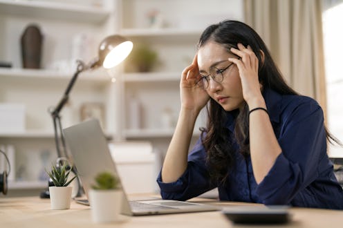 Shot of young businesswoman with headache and looking stressed out while working in an office.