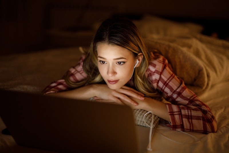 Portrait of a young woman watching a movie at night in her bedroom