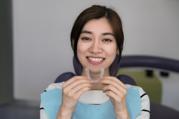Young female holding an invisible dental aligner