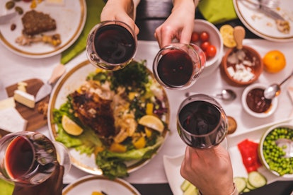 Directly above shot of four unrecognizable friends sitting around dining table and making celebrator...