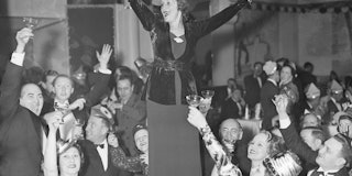 A woman stands on a table to raise a toast to the New Year at a New Year celebration in a New York y...