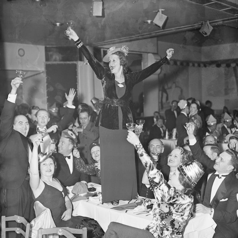 A woman stands on a table to raise a toast to the New Year at a New Year celebration in a New York y...