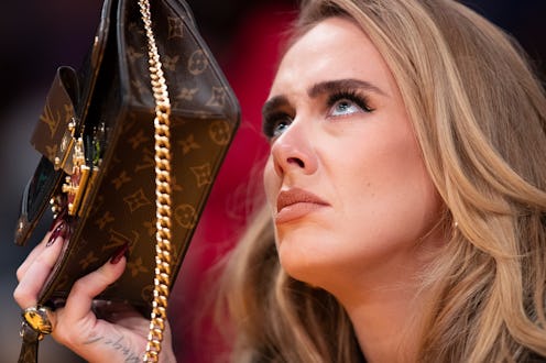 Singer Adele uses her purse to hide from the TV camera while she sings along to her song