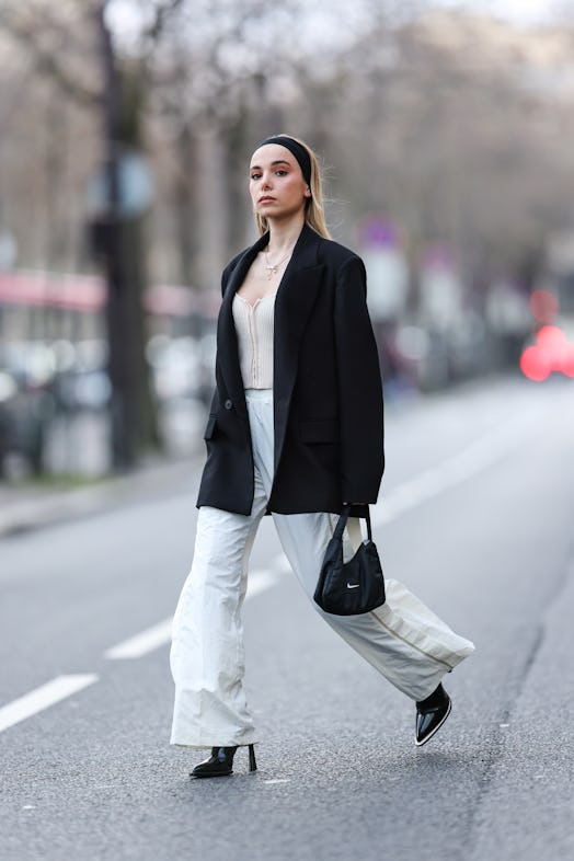 Anne-Sophie Da Fonseca wears a white large jogger pants from Nike with a black pointed shiny boots f...