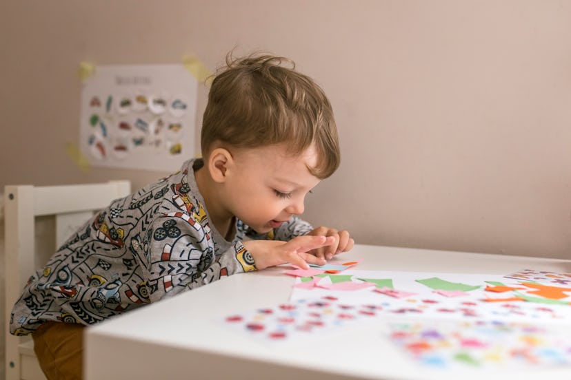 A little boy at table playing with stickers, demonstrating a potential for perfectionism, a fact abo...