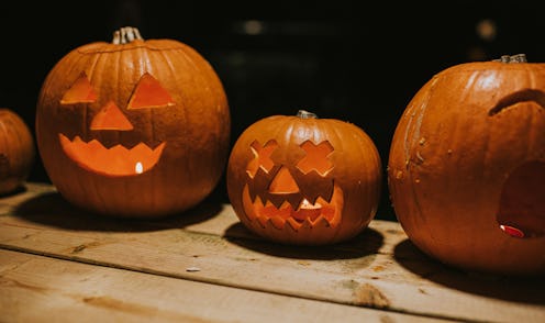 A line up of ripe orange pumpkins, scooped out and carved as a hallowe'en decoration, traditional in...