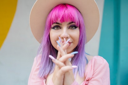 Young woman with pink hair and long nails, thinking about her January 17, 2022 weekly horoscope.