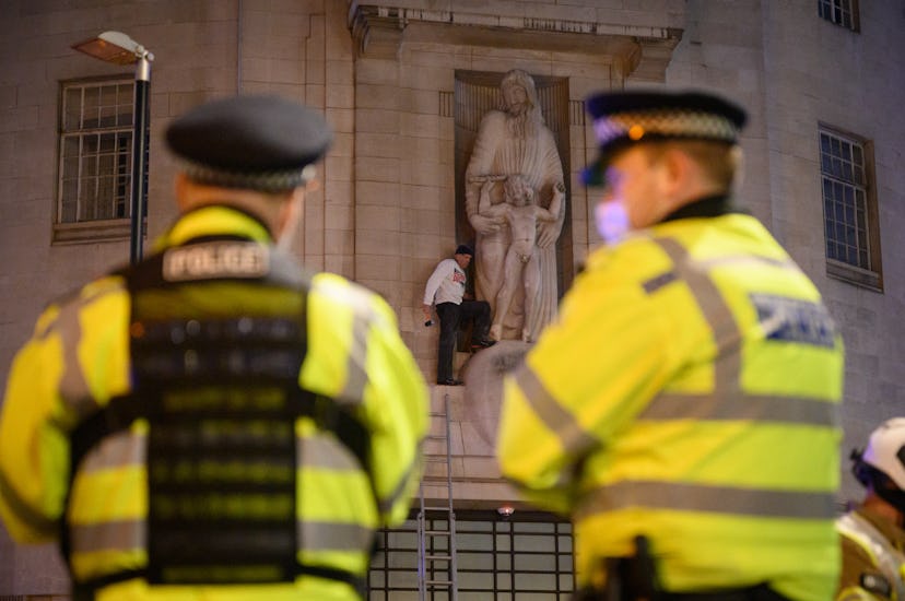 LONDON, ENGLAND - JANUARY 12: Police officers look on as a protester attempts to damage a statue by ...