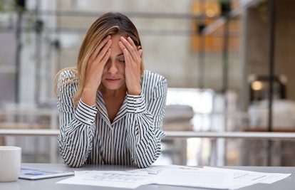 Stressed business woman having a headache at the office and looking very worried. **DESIGN ON ALL DO...