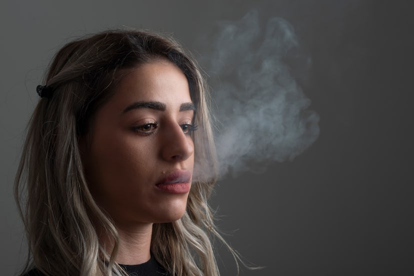 Studio portrait of young woman smoking on gray background.Studio shot