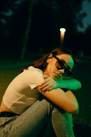 Young woman leaning over knees, thinking about the January 24, 2022 weekly horoscope for her zodiac ...