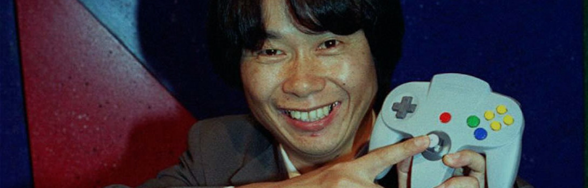 Video game designer, Shigeru Miyamoto from Japan, points to the handset of the new Nintendo 64 flags...