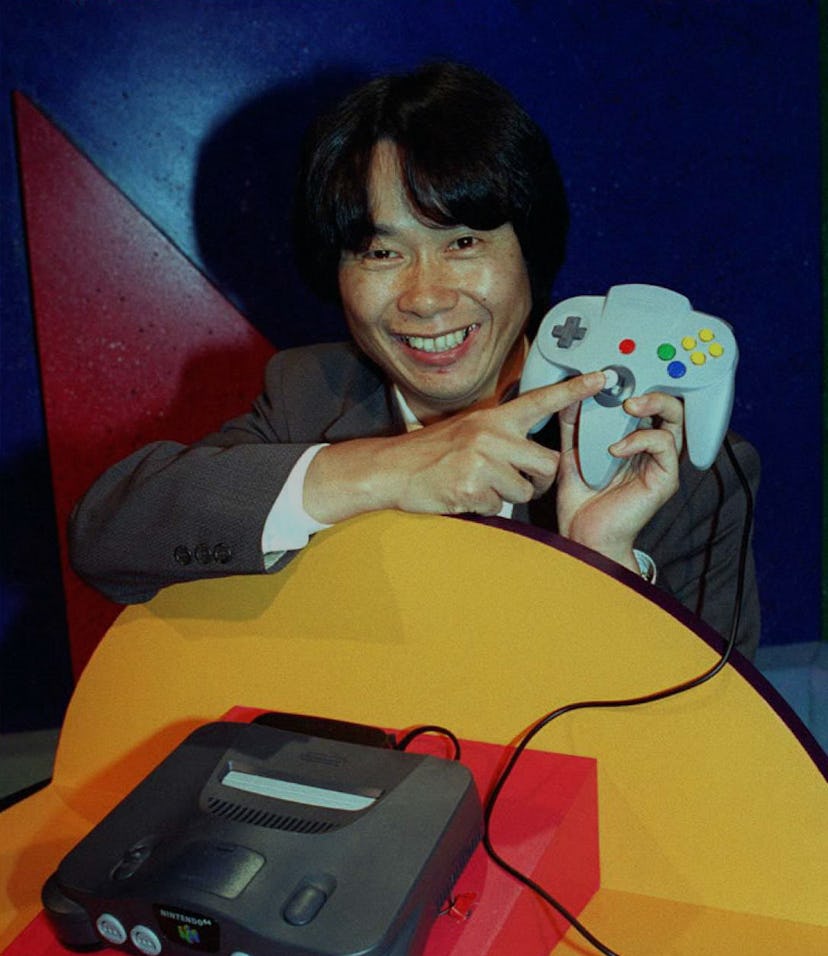 Video game designer, Shigeru Miyamoto from Japan, points to the handset of the new Nintendo 64 flags...