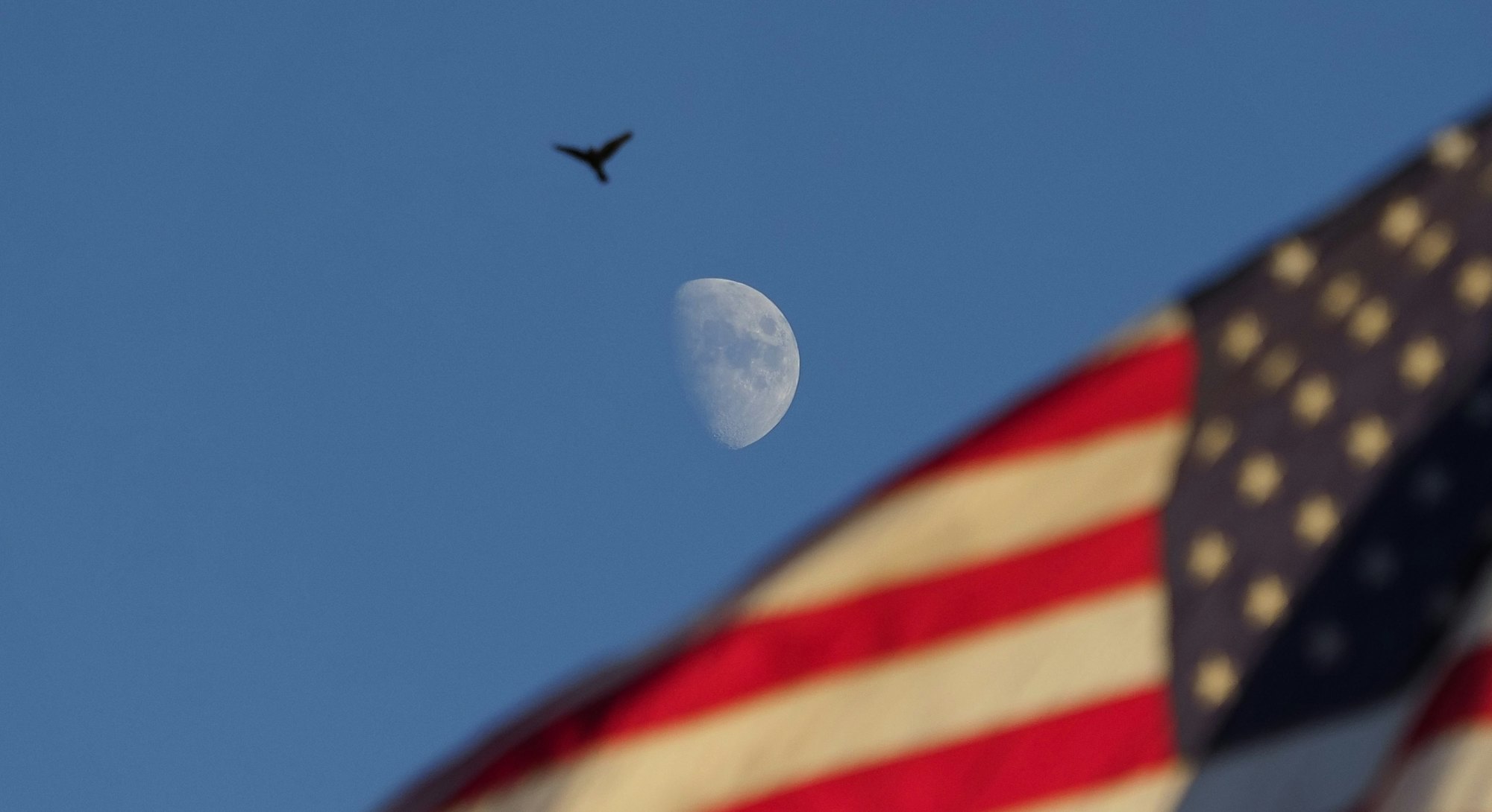 The United State's flag waving in the sky with the moon in the background. The United State's first ...