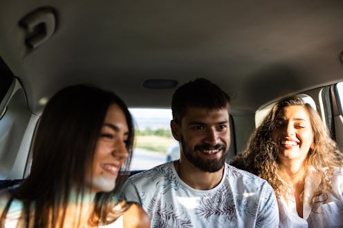 A group of friends are having a great time in the back seat on a road trip