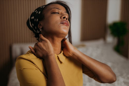 A stressed woman massages her neck. Here's your daily horoscope for January 18 2022.
