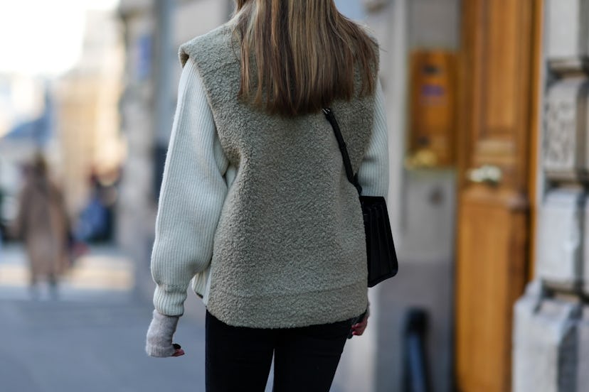 PARIS, FRANCE - JANUARY 05: A passerby wears a white wool ribbed pullover, a gray fluffy sleeveless ...