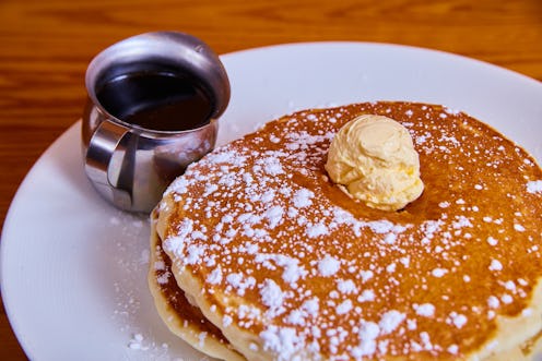 Image of Classic stack of pancakes sprinkled with powdered sugar and topped with butter dollop and s...