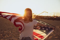 Woman holding an american flag on the beach. Here's how the United States' pluto return in 2022 will...