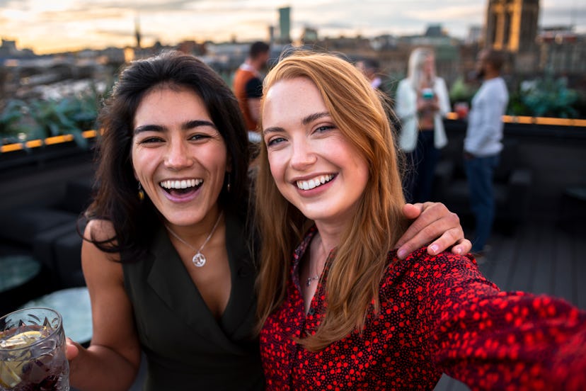 A selfie shot of two female friends at a rooftop bar in Newcastle Upon Tyne. They are looking and sm...