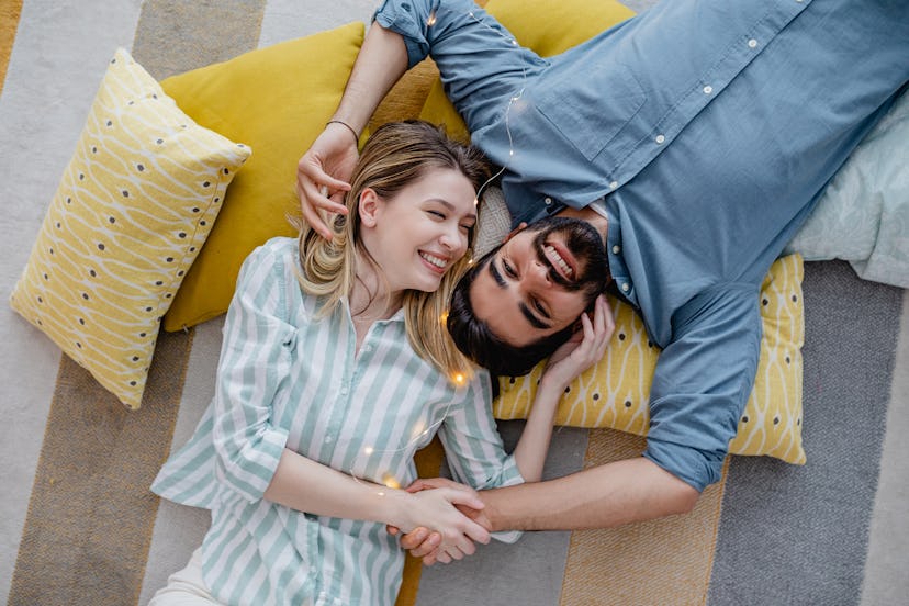 A young couple is at home in a living room at home on the floor, hugging and smiling