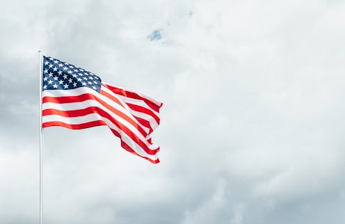 USA America flag waving in the wind over cloudy sky low angle view.