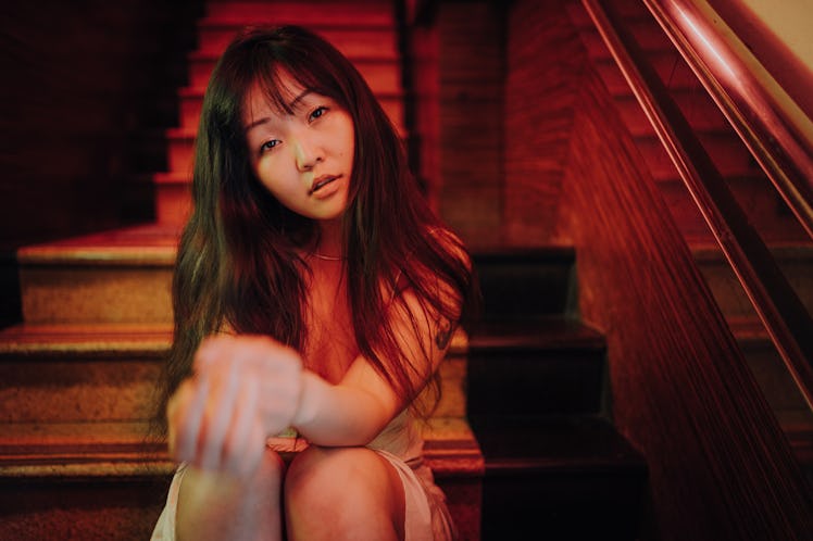 Young woman sitting on stairs, thinking about how her unlucky zodiac sign will have the worst week o...