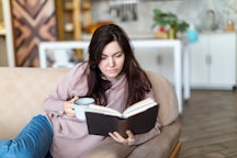 Young woman resting at home reading book
