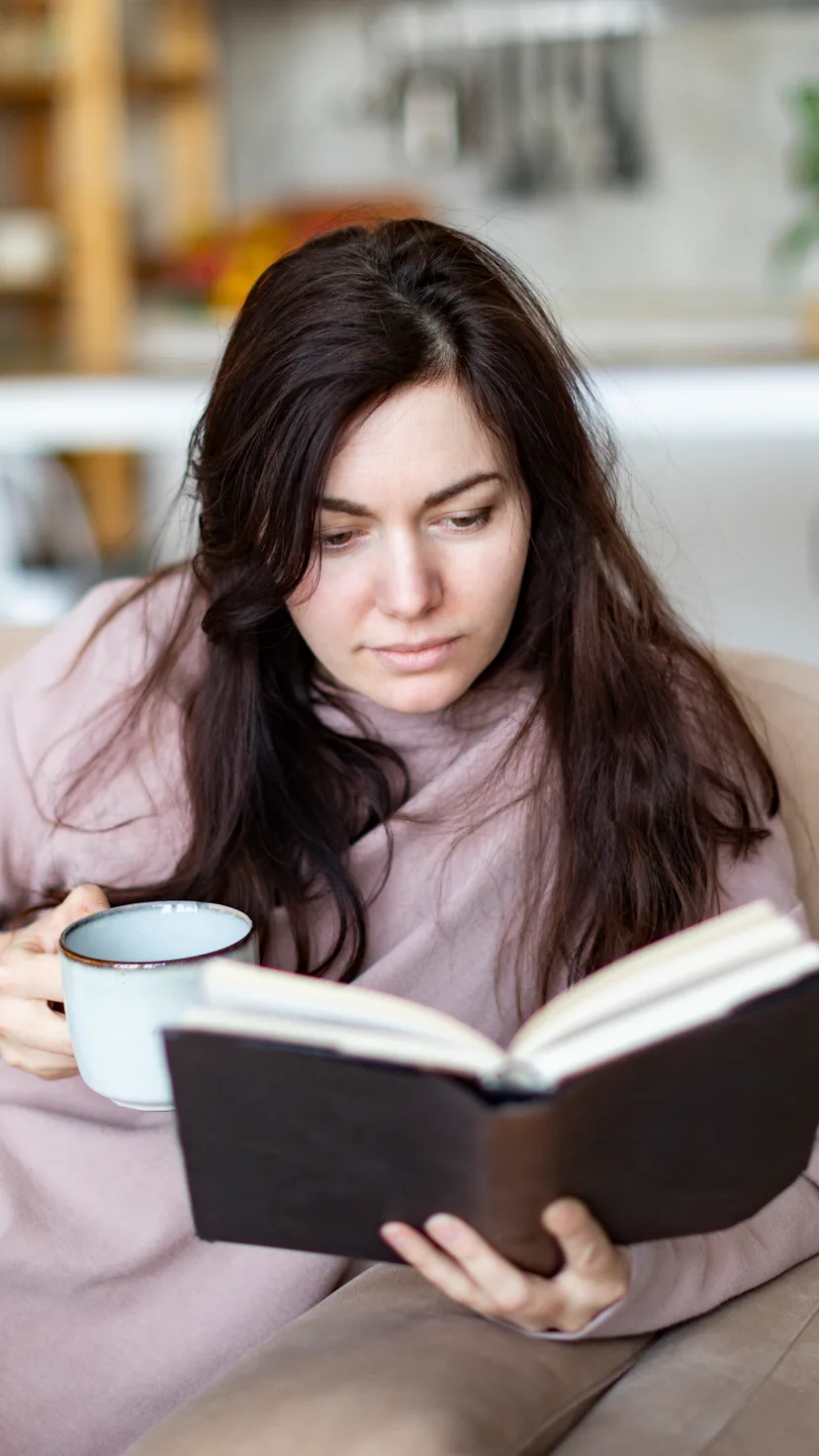 Young woman resting at home reading book