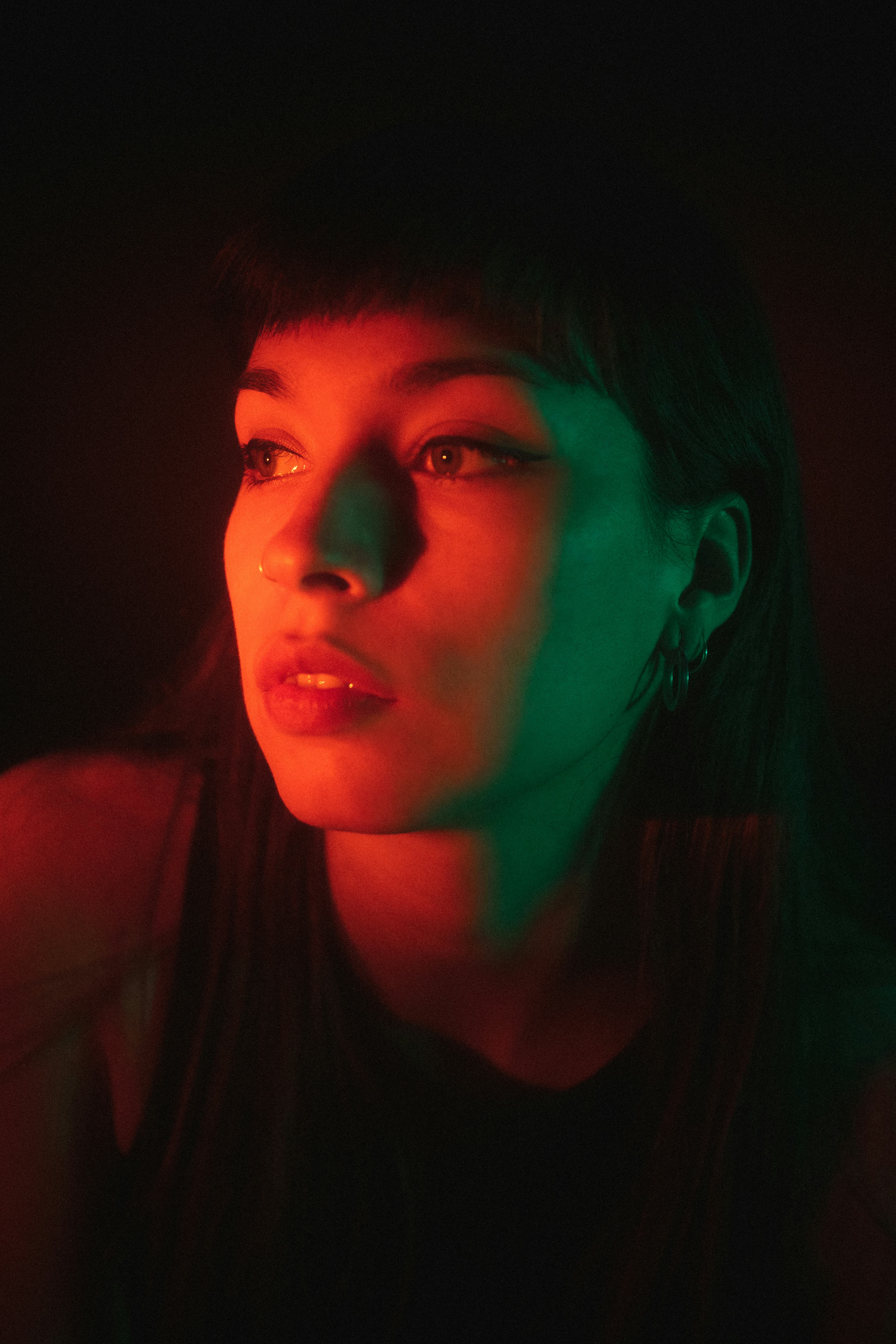 young woman poses while being lit by neon lights as she reflects on the zodiac signs most likely to ...