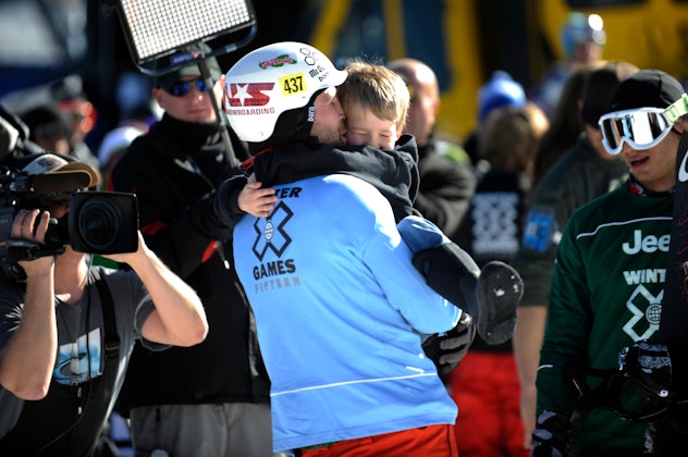 Nick Baumgartner hugs his son, Landon, 6, after winning the men's Snowboarder X finals at the Winter...