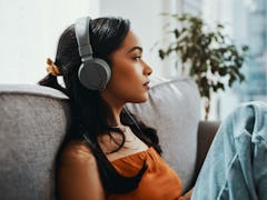 Shot of a young woman using headphones while relaxing on the sofa at home