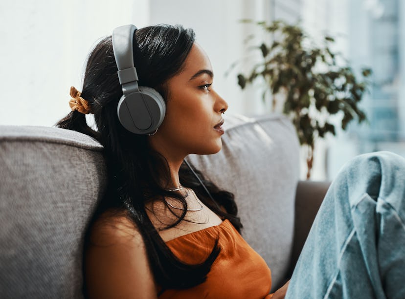 Shot of a young woman using headphones while relaxing on the sofa at home