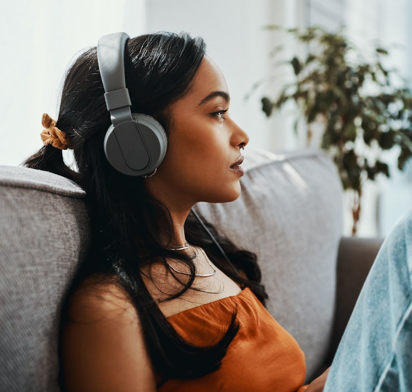 Shot of a young woman using headphones while relaxing on the sofa at home