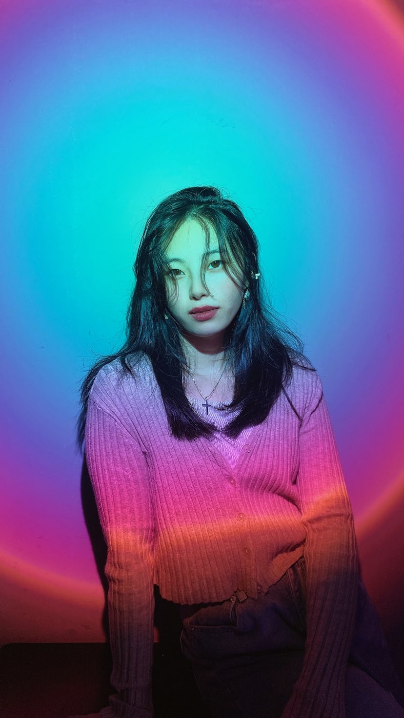 Girl sitting in front of a neon light. Aquarius season 2022 arrives on Jan. 20.