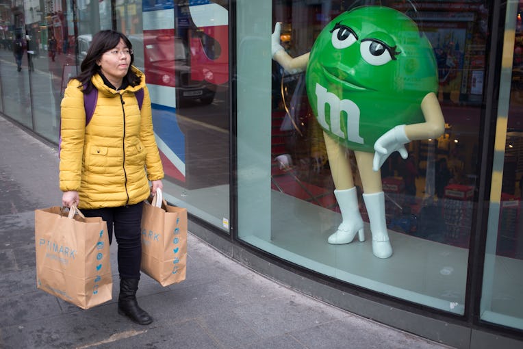 Woman walking past the M&Ms store with her Primark shopping bags. London, UK. (Photo by In Pictures ...