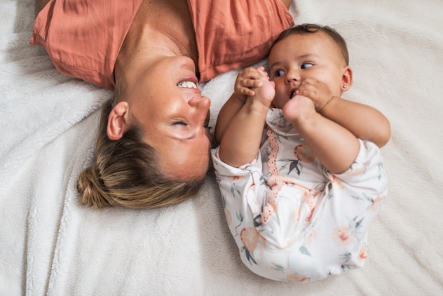 Happy mother and baby playing in bedroom.